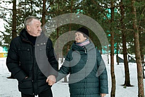 Cute mature couple experiencing love for each other while walking in the park in winter