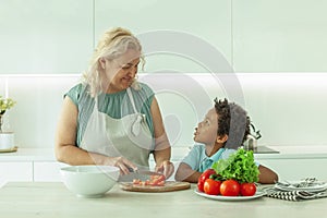 Cute mature woman and her son preparing healthy food together standing at a worktop in the kitchen