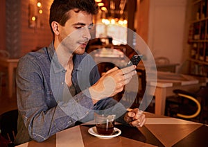 Cute millenial male texting in restaurant photo