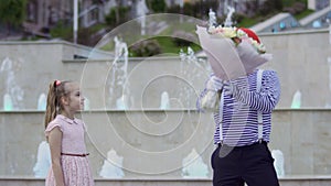 Cute mime in red beret give bouquet of flowers to a little girl