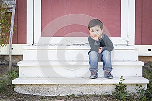 Cute Mixed Race Boy Sitting on the Steps of a Barn