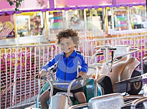 Cute mixed race little boy enjoying a ride on a fun carnival carousel ride.