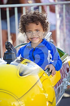 Cute mixed race little boy enjoying a ride on a fun carnival carousel ride. A happy boy Smiling and having fun riding a amusement