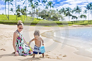 Cute mixed race little boy playing in the sand the beach with his mother
