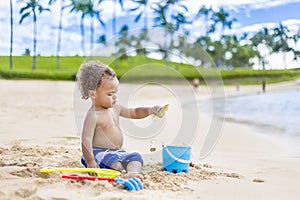 Cute mixed race little boy playing in the sand on a tropical beach vacation