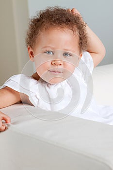 Cute mixed raced little girl smiling sitting on a sofa.