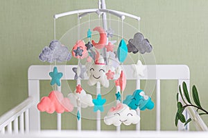 Cute mobile with clouds, stars and moon hanging on a crib in a children\'s room.