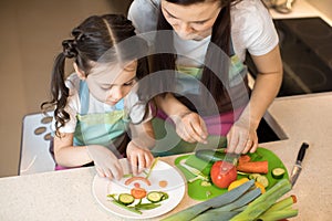 Cute mom and her kid making funny face from vegetables