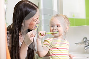 Cute mom teaching child teeth brushing