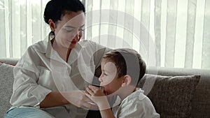 Cute mother gives her preschooler son a glass of water, the child drinks water from a glassglass while sitting on the