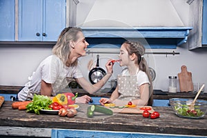 Cute mother gives to her dother a piece of Bulgarian pepper to taste