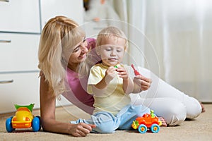 Cute mother and kid boy playing together indoors at home