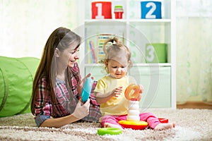 Cute mother and kid girl playing indoor at home