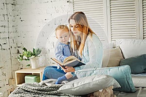 Cute Mother Reading a Book to her Son at Home