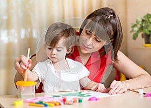 Cute mother teach her daughter kid to paint