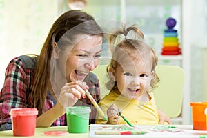 Cute mother teach her daughter kid to paint