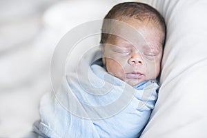 Cute multi-racial Newborn baby boy sleeping in a blanket