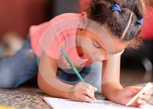 Cute multiracial small girl drawing on a coloring book