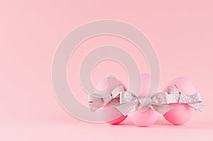 Cute and naivety easter background with pink eggs group with grey bows on pastel pink backdrop.