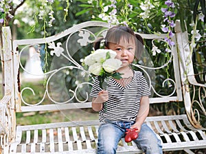 Cute naughty lovely adorable little girl carry a bunch of flowers and sit on a bench have fun outdoor in summer park happy