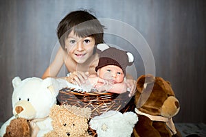 Cute newborn baby boy in basket with teddy bear hat, looking at
