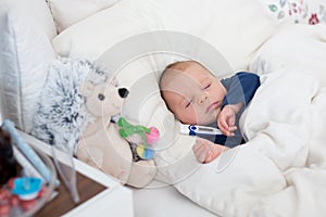 Cute newborn baby boy, lying in bed with cold