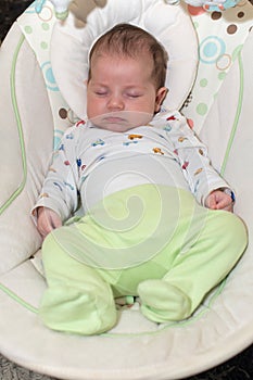 Cute newborn baby boy, sleeping in a swing