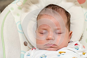 Cute newborn baby boy, sleeping in a swing