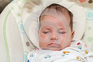 Cute newborn baby boy, sleeping in a swing