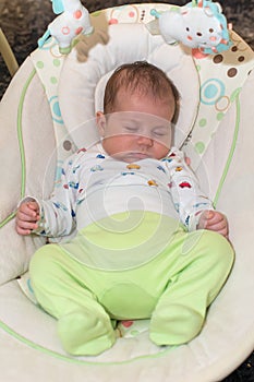 Cute newborn baby boy, sleeping in a swing