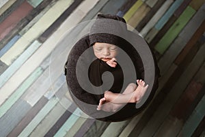 Cute newborn baby on a brown blanket. Sleeping baby on a dark background. Closeup portrait of newborn baby. Baby goods packing tem