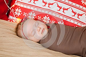 Cute newborn baby in a Christmas costume on a bed at home