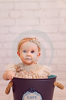 Cute newborn baby in creative decoration bucket bag. Infant girl sitting inside bowl. Pinky colours