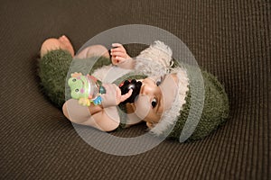 Cute newborn baby in the dark green hat. Happy baby on a green background. Closeup portrait of newborn baby. Baby goods packing te