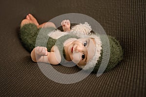 Cute newborn baby in the dark green hat. Happy baby on a green background. Closeup portrait of newborn baby. Baby goods packing te