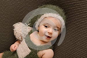 Cute newborn baby in the dark green hat. Happy baby on a green background. Closeup portrait of newborn baby. Baby goods packing te