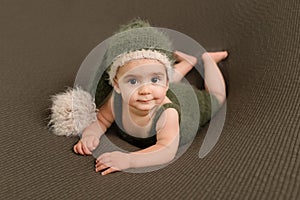 Cute newborn baby in the dark green hat. Happy baby on a green background. Closeup portrait of newborn baby. Baby goods packing te