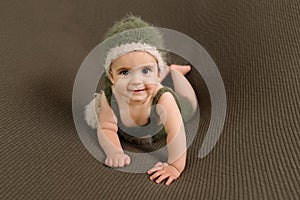 Cute newborn baby in the dark green hat. Happy baby on a green background. Closeup portrait of newborn baby. Baby goods packing te