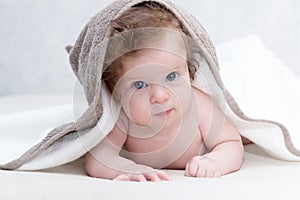 Cute newborn baby girl with beautiful blue eyes on a white terry coverlet. Adorable baby looking out under a white