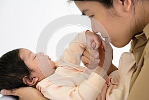 Cute newborn baby girl or boy sleeping on mother hand at home. Mom kissing infant hand with love