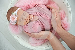 Cute newborn baby girl with her father on light background