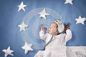 Cute newborn baby girl lying in the bed. 2 month old child in owl hat sleeping on blue blanket