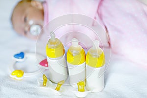 Cute newborn baby girl with nursing bottles and pacifier