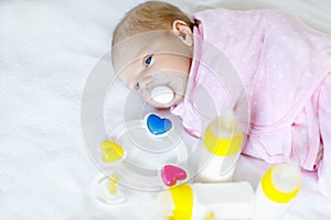 Cute newborn baby girl with nursing bottles and pacifier