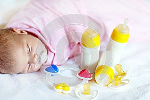 Cute newborn baby girl with nursing bottles and pacifier