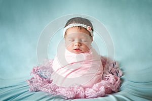 Newborn baby girl peacefully sleeping in a potato sack pose