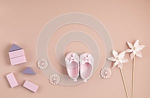 Cute newborn baby girl shoes with festive decoration over pink background. Baby shower, birthday, invitation or greeting card