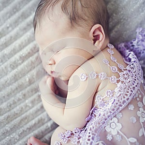 Cute newborn baby girl sleeping on blanket covered with lace