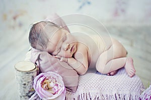 Cute newborn baby girl sleeping on wooden bed with flowers