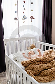 Cute newborn baby lying in the crib at home